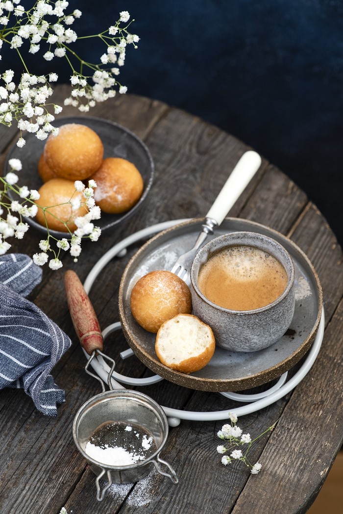 Coffee and pastries with powdered sugar on a wooden table