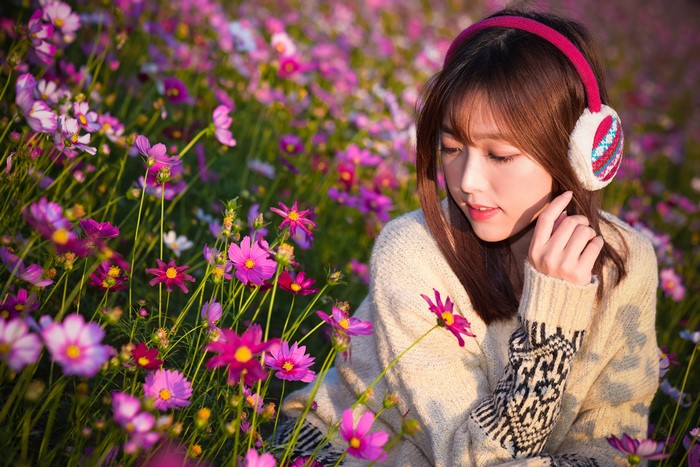 Asian girl with headphones in a field of flowers