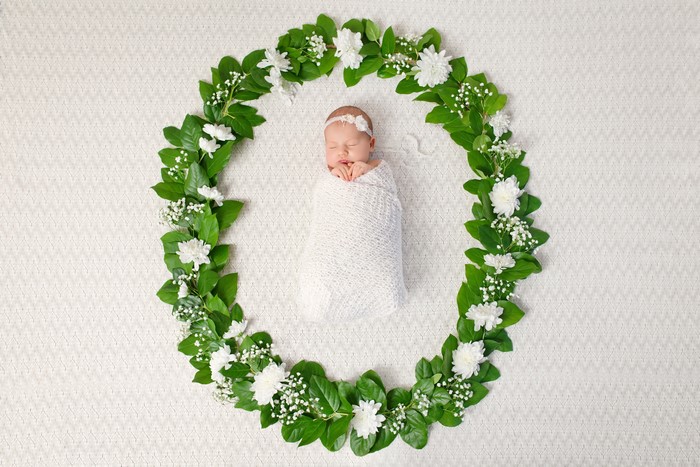 Newborn baby sleeping in a floral wreath
