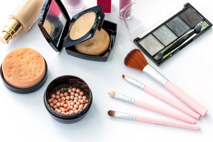 Makeup products and brushes on a white background