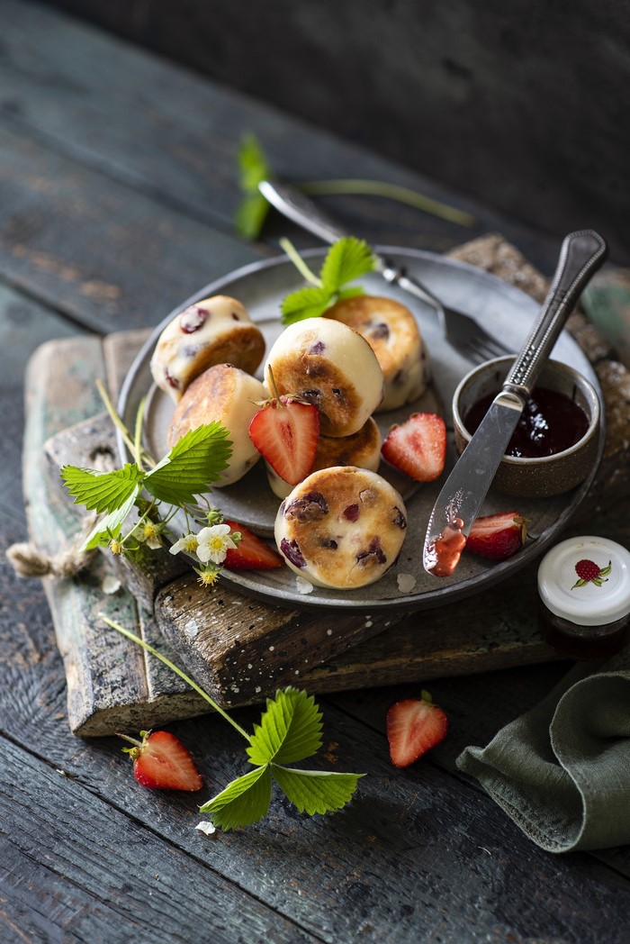 Pancakes with strawberries and jam on a wooden table