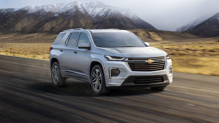 Silver Chevrolet Traverse driving on a road with mountains