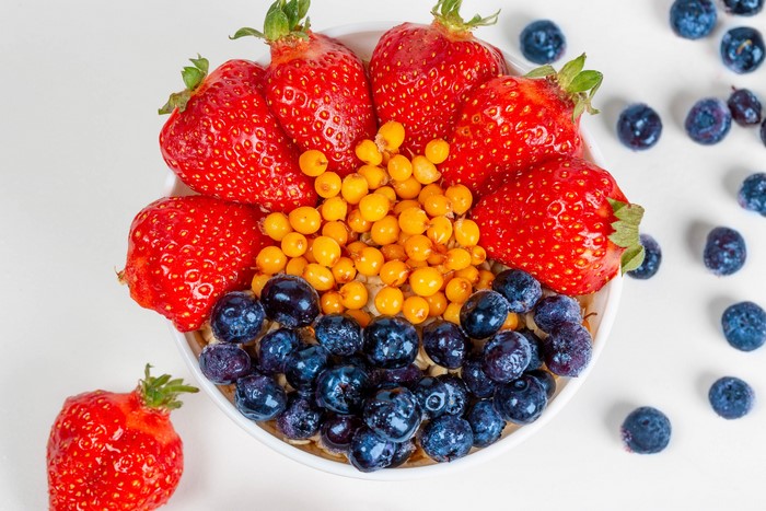 Bowl of oatmeal with strawberries, blueberries, and sea buckthorn