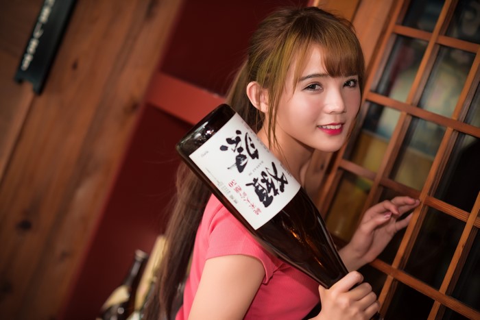 Asian woman holding a bottle of sake