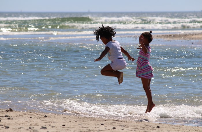 Two little girls jumping in the sea