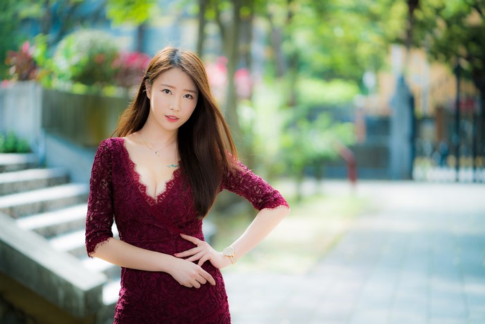 Asian woman in a maroon dress posing outdoors