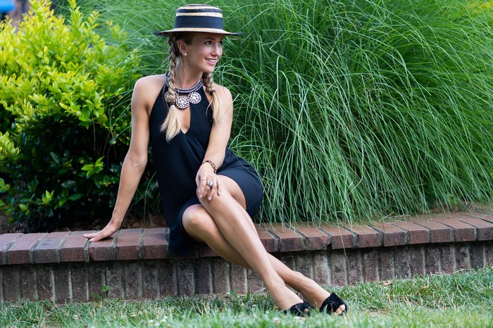 Woman in Black Dress and Hat Sitting by Plants