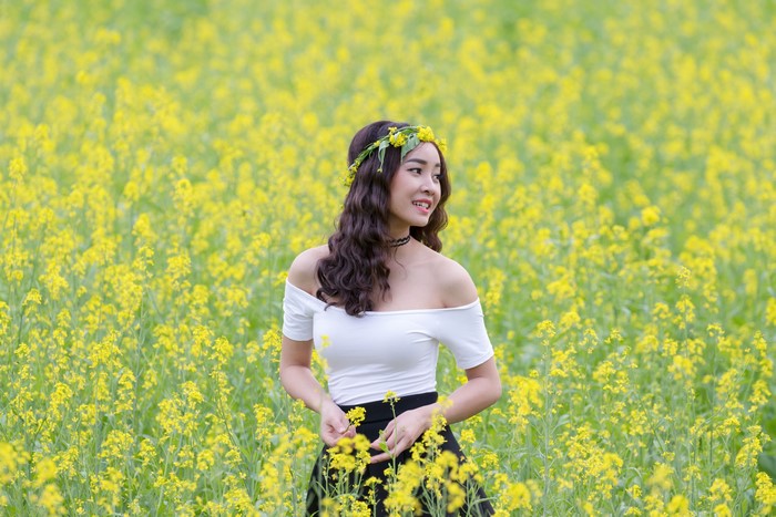 Asian woman with flower wreath in rapeseed field
