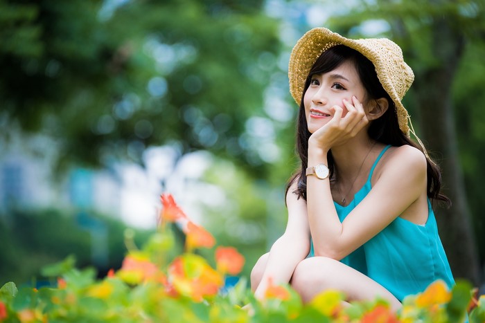 Asian girl in a hat sitting in a garden