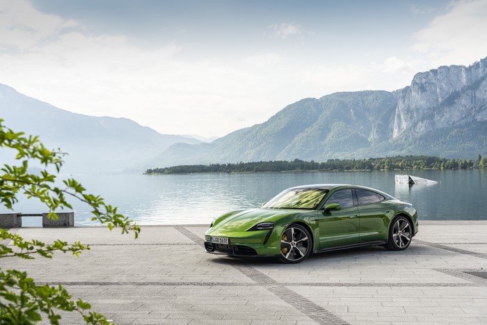 Green Porsche Taycan by a lake with mountains