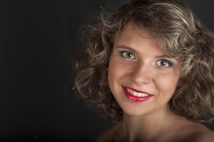 Woman with curly dark blonde hair and red lips