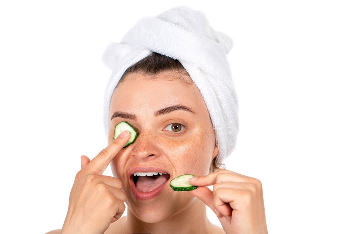 Woman with cucumber slices on eyes and towel on head