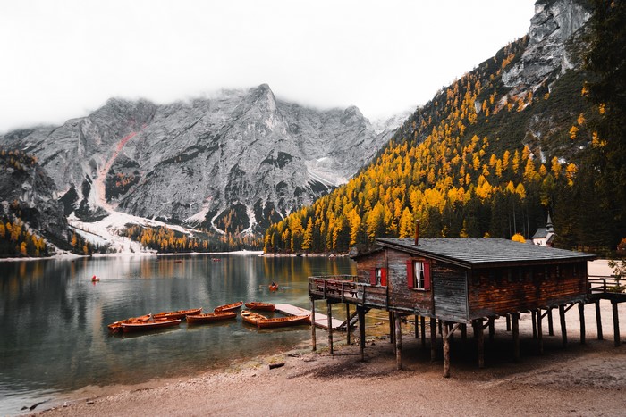 Wooden boathouse on stilts by a lake with boats and mountains
