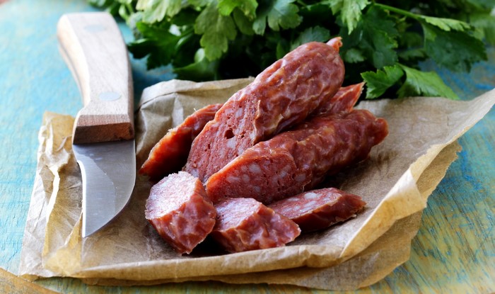 Sliced sausage with a knife and parsley