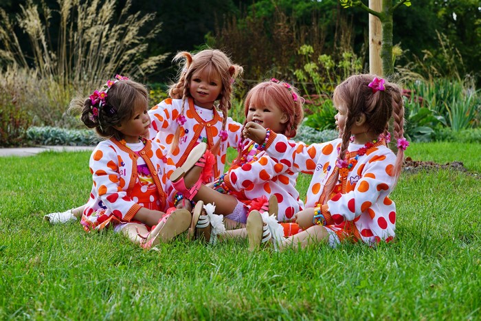 Four dolls sitting on grass in Grugapark Essen