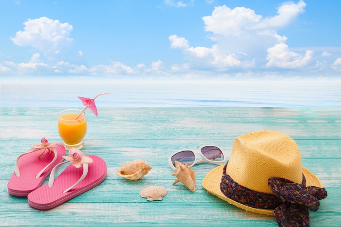Summer beach scene with flip-flops, hat, and drink