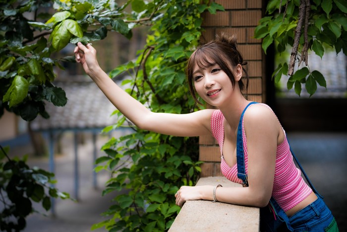 Asian woman with brown hair touching leaves