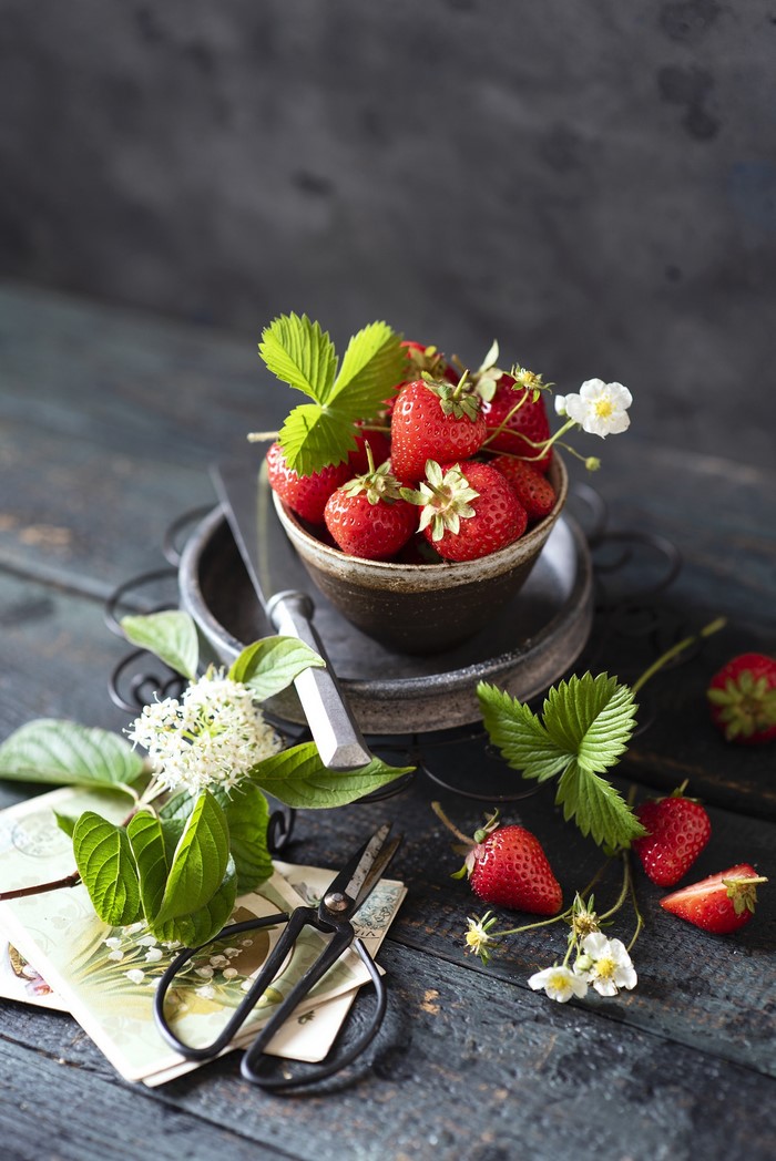 Strawberries in a bowl with flowers and scissors