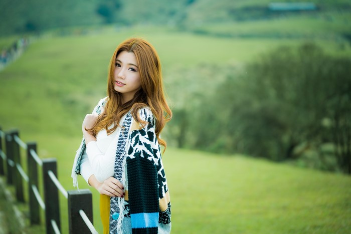Asian woman with brown hair wearing a colorful cardigan