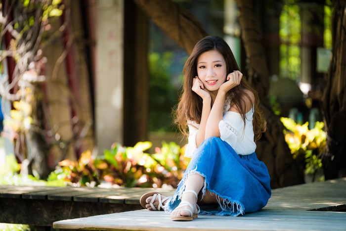 Asian woman with brown hair sitting outdoors