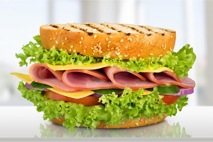 Sandwich with ham, cheese, lettuce, tomato, and onion