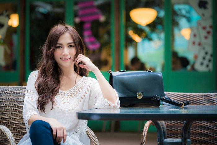 Asian woman with brown hair sitting with handbag