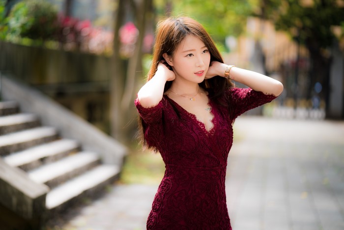 Asian woman in a burgundy dress with hands in hair