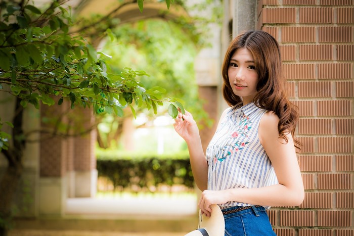 Asian woman with brown hair holding a hat