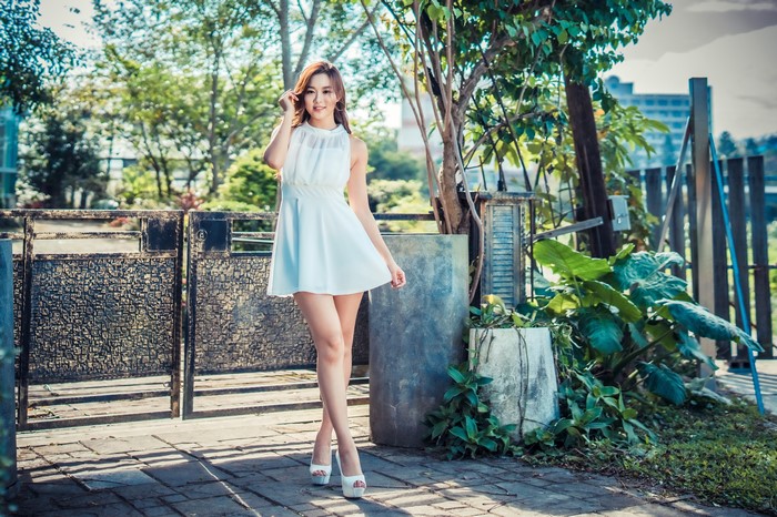 Asian woman in white dress posing outdoors