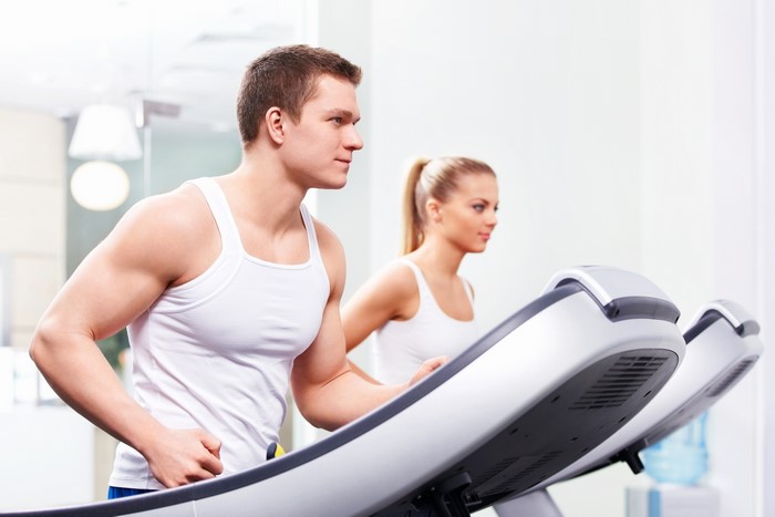 Man and woman running on treadmills in a gym