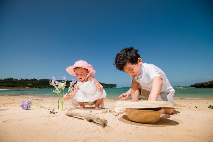Two children playing on a beach with flowers