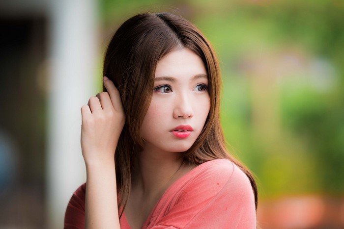 Asian woman with brown hair touching her ear