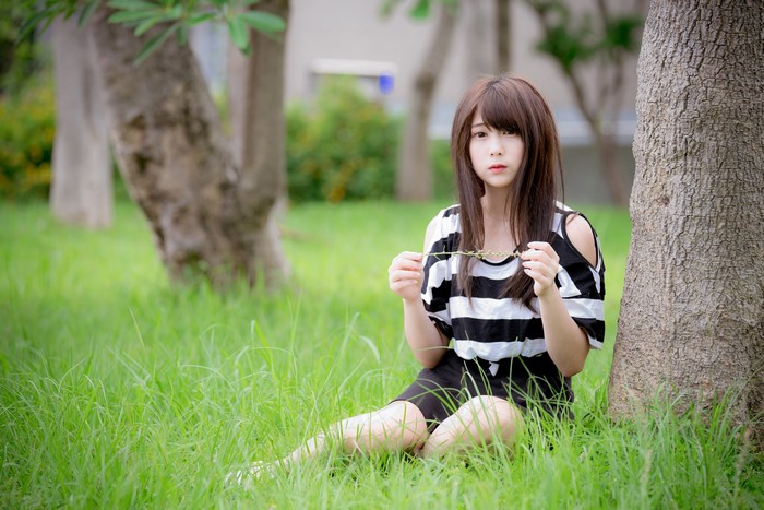 Asian girl with brown hair sitting in grass