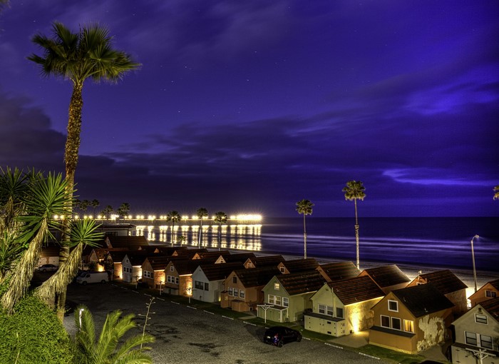 Beachfront houses at night with pier and palm trees