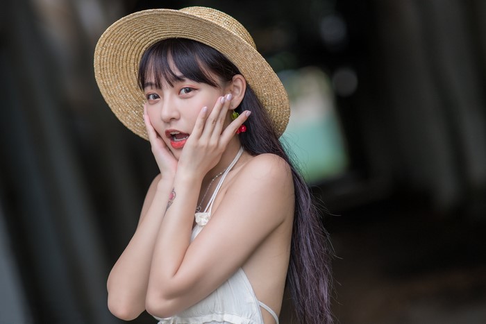 Asian woman wearing a straw hat with cherry earrings