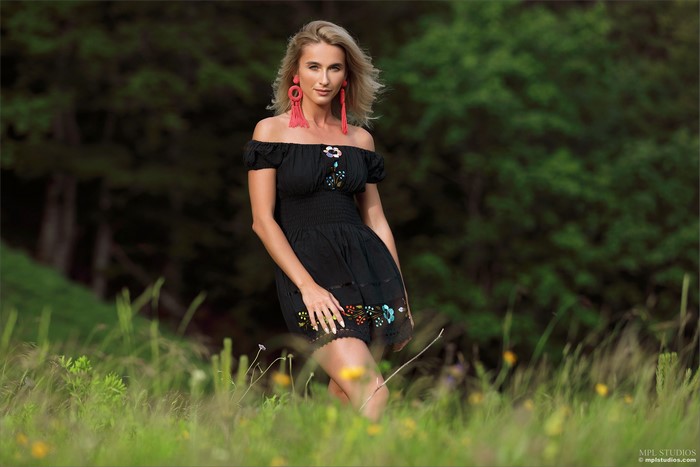Blonde girl in a black dress in grass