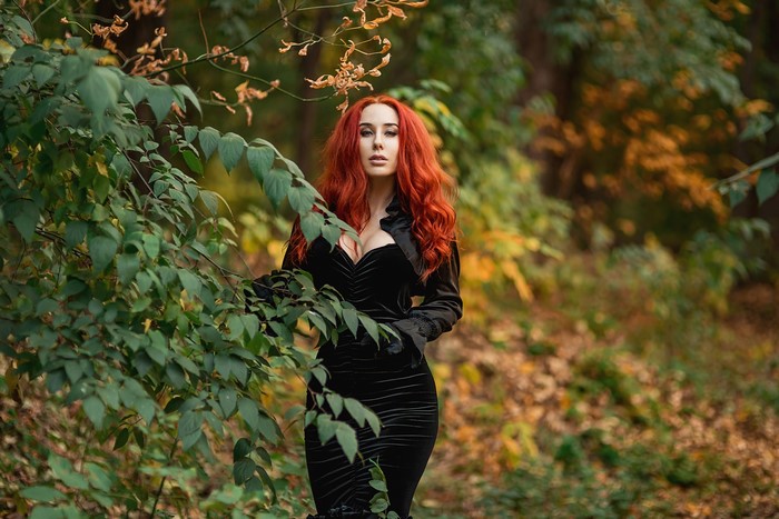Redhead woman in black dress in autumn forest