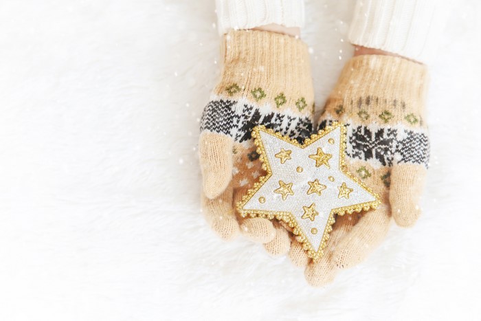 Hands in patterned gloves holding a star decoration