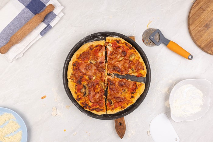Pizza in a frying pan with pizza cutter