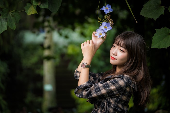Asian woman with brown hair wearing a watch and plaid shirt