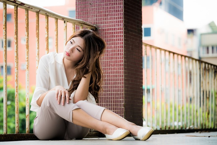 Asian woman with brown hair sitting on balcony