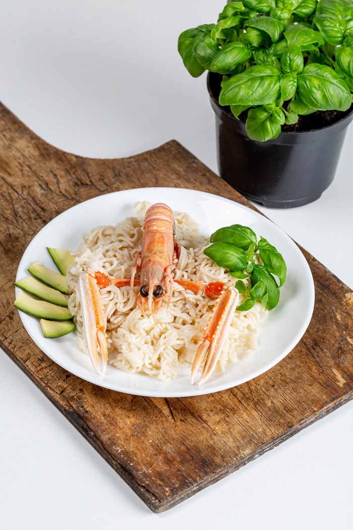 Scampi pasta with avocado and basil on a cutting board