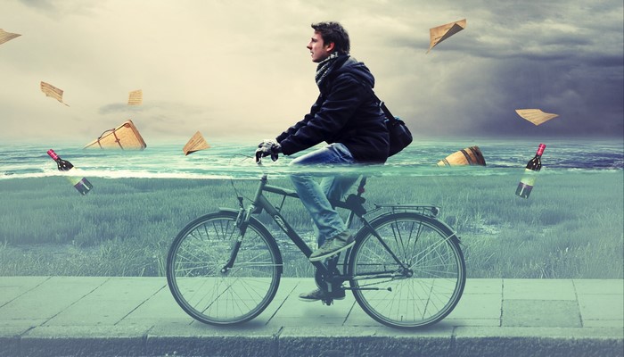 Man riding a bicycle through water with floating objects
