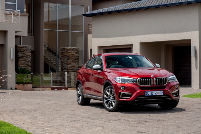 Red BMW X6 Sports Activity Coupe parked in front of a modern house