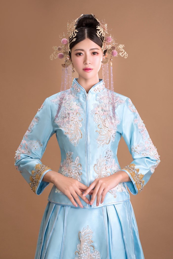 Asian woman in traditional blue wedding dress with ornate headpiece