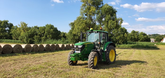 John Deere 620M Tractor in a Field with Hay Bales