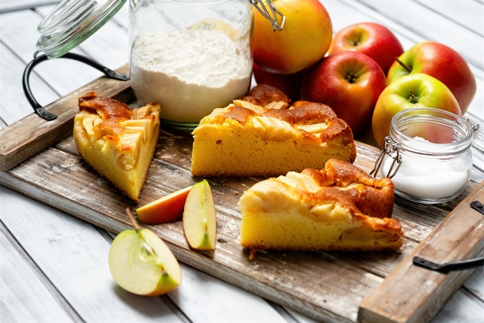 Apple pie slices with apples, flour, and sugar on a cutting board