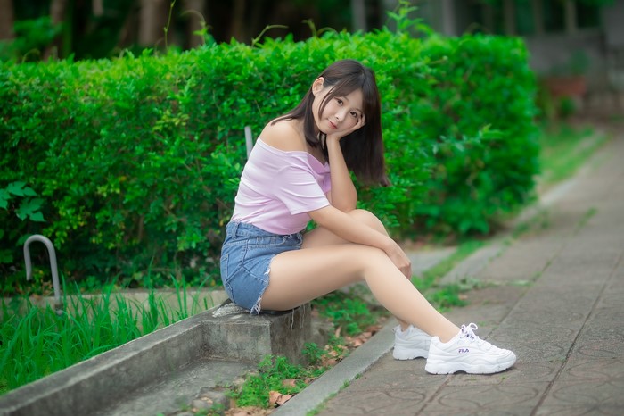 Asian woman sitting by a hedge