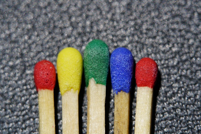 Five multicolored matches on a textured surface