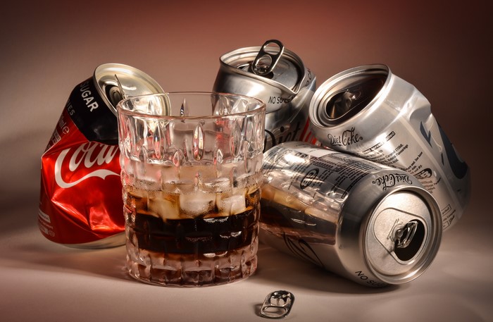 Coca-Cola and Diet Coke cans with a glass of soda